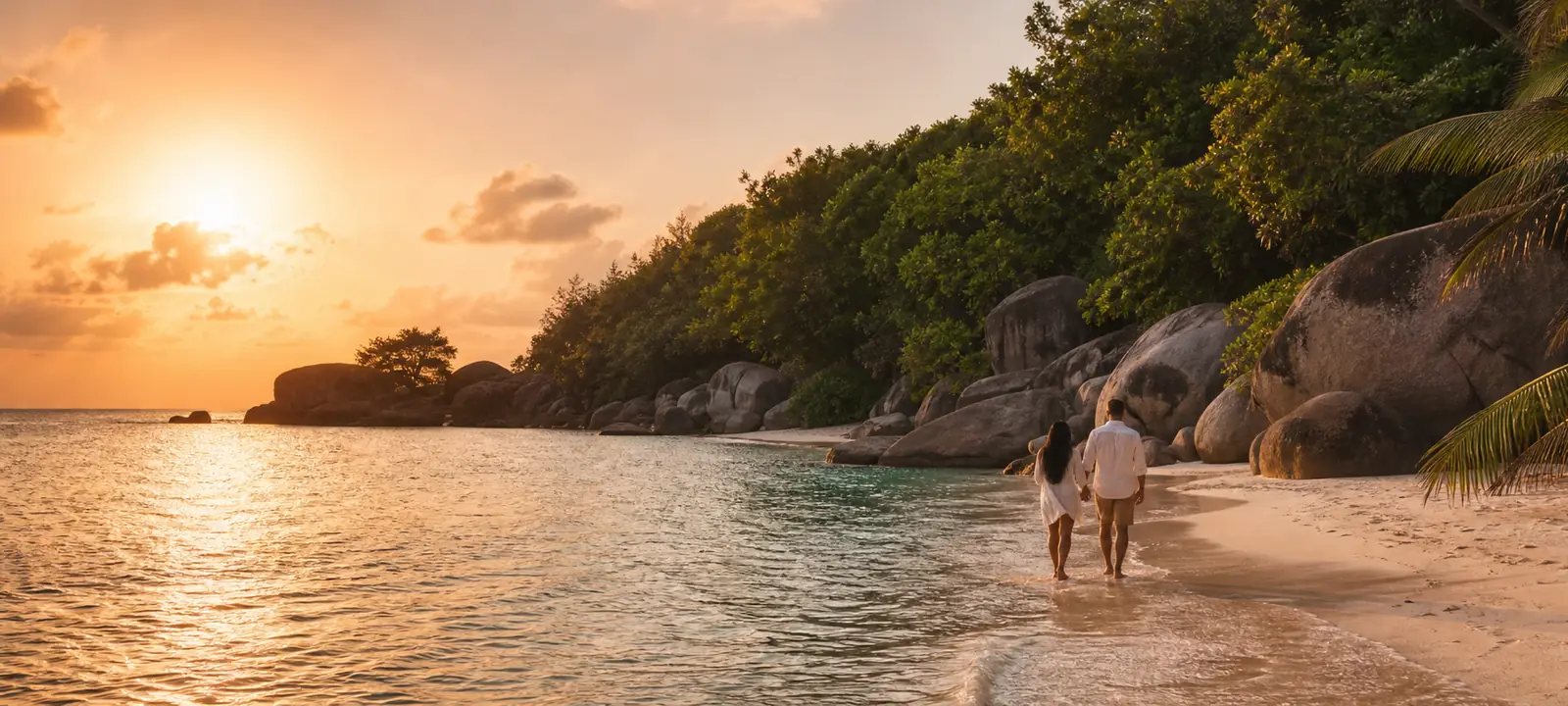 A couple walking along a quiet tropical shoreline at sunset.